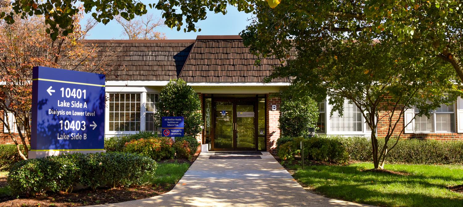 Tree-lined entrance to a brick professional building with white shutters on the campus of MedStar Southern Maryland Hospital Center