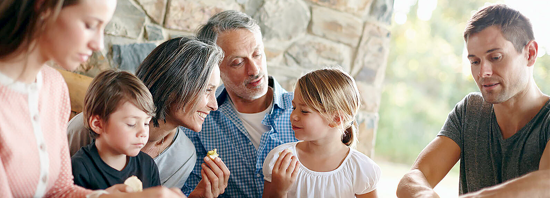 A multigenerational family shares a meal together outdoors.