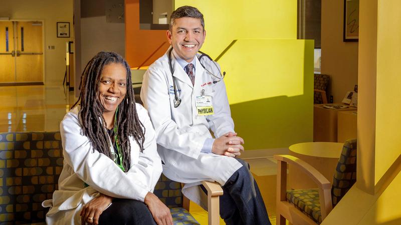 Two former GME students pose for a photo in a hospital lobby.