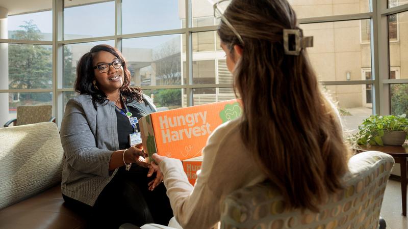 A patient receives a boxed meal from Hungry Harvest, which contains three nonperishable meals—breakfast, lunch, and dinner.