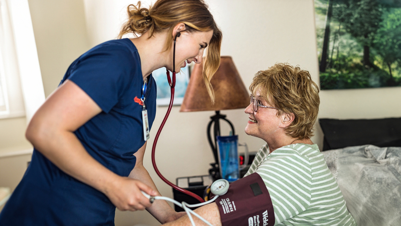 A home health care nurse checks a patient's blood pressure.