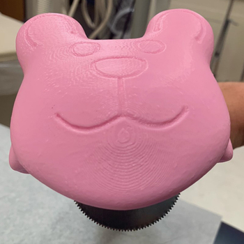 A close-up photo of a cast saw cover in the shape of a pink teddy bear, used to cut the casts off of pediatric orthopedic patients.