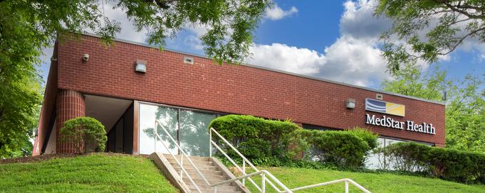 A red brick and glass office building at the top of a hill is home to MedStar Health Primary Care at Kirk Avenue in Baltimore, MD.