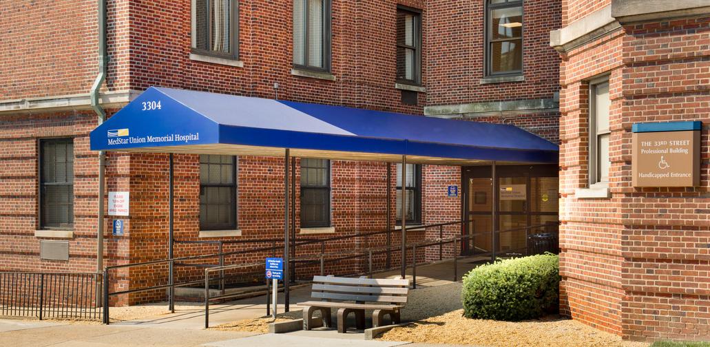 MedStar Health Neuroscience at Baltimore is located in a large brick building with a long entry way covered by a blue awning. The street number and MedStar Health logo are on the front of the awning.