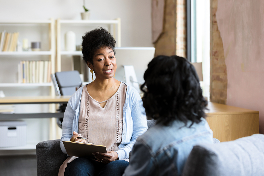 A young woman talks with a therapist in an office setting.