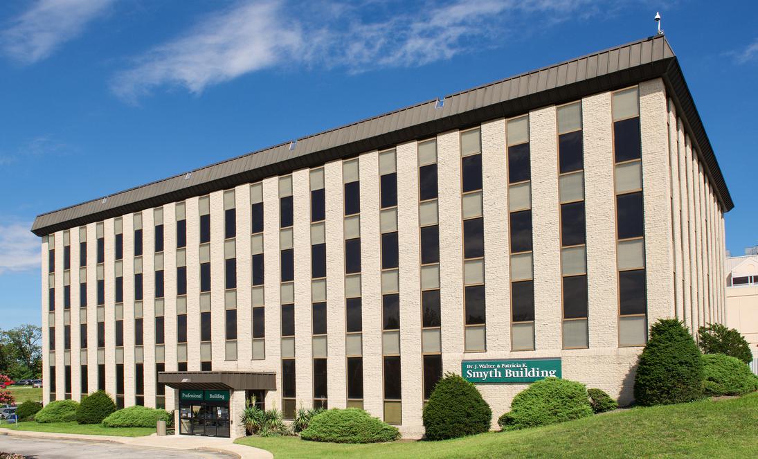 The Smyth Building on the campus of MedStar Good Samaritan Hospital in Baltimore, is a late-20th century concrete and glass building with a green sign.