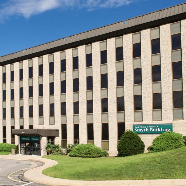 The Smyth Building on the campus of MedStar Good Samaritan Hospital in Baltimore, is a late-20th century concrete and glass building with a green sign.