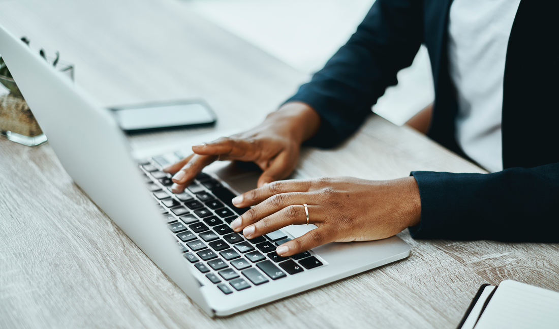 Close up photo of hands typing on a laptop computer keyboard