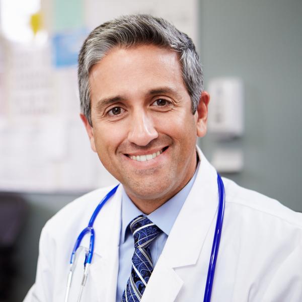 Portrait Of Doctor Working At Nurses Station Smiling At Camera