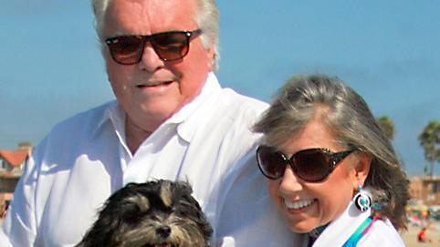 Bill and Carolyn Bivens pose for a photo outdoors with their dog.