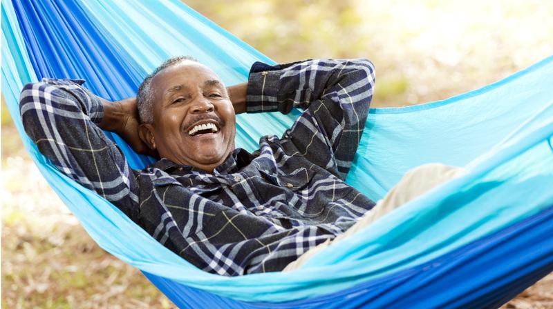 A man relaxes outdoors in a hammock.
