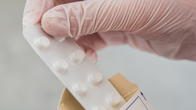 Close up photo of a hand holding pills in a blister pack.