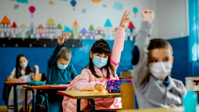 Children wearing masks in a school classroom.