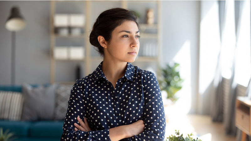 A woman looks out the window of her home.