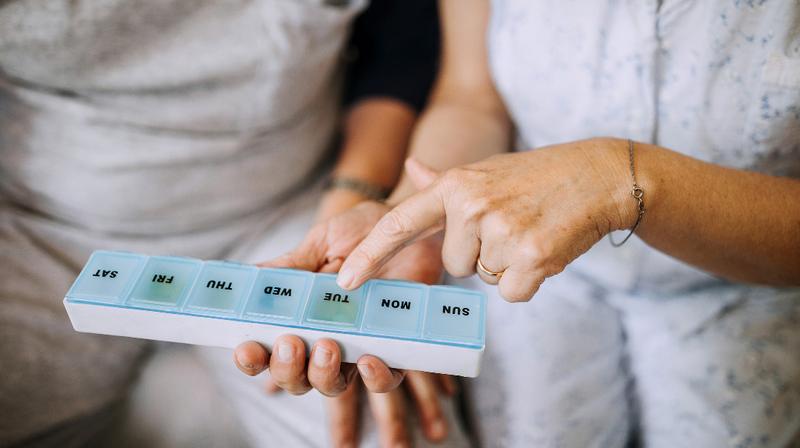 Close up photo of a woman's hands holding a weekly pill organizer box.
