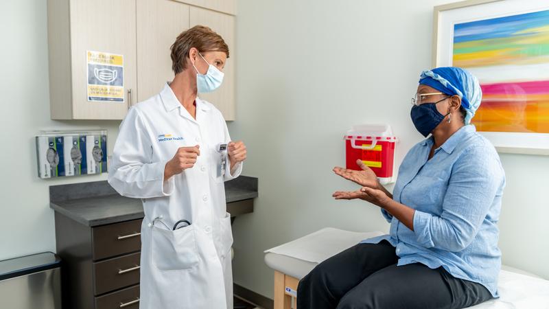 A female doctor consults with an african american female patient in a clinical setting.