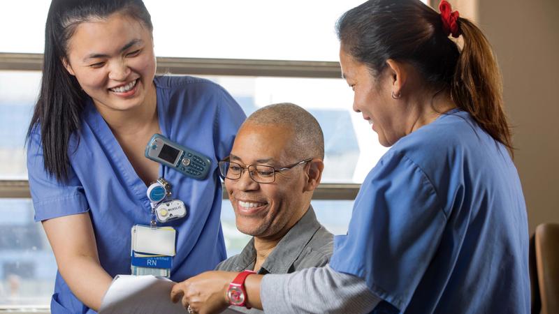 Two nurses talk with a patient at MedStar Health.