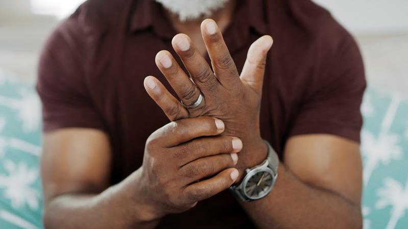 Close up photo of an african american man massaging his aching hand.