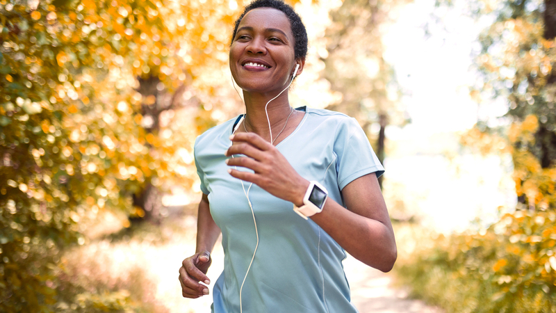 A young woman runs outdoors in a forest setting.