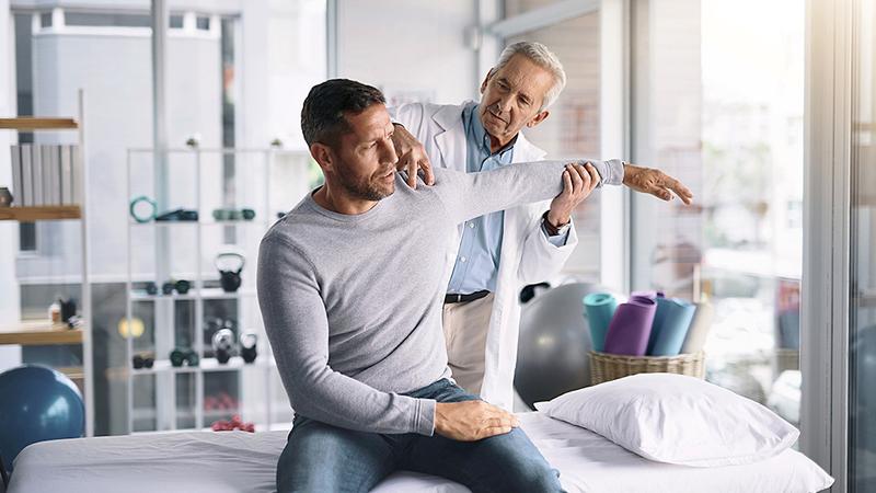 A doctor examines a patient's shoulder during an office visit.