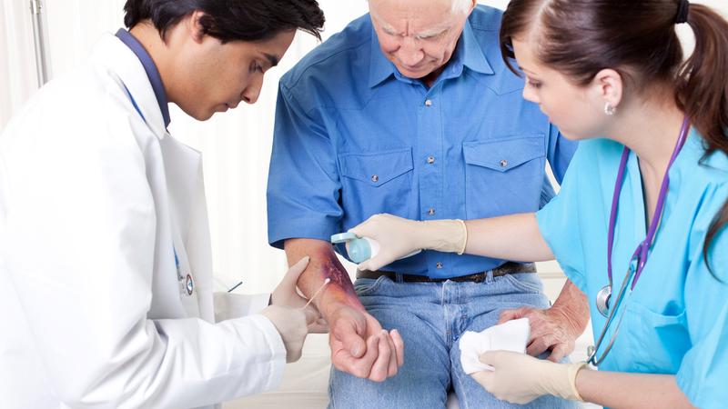 A doctor and nurse treat a patient with a burn wound.