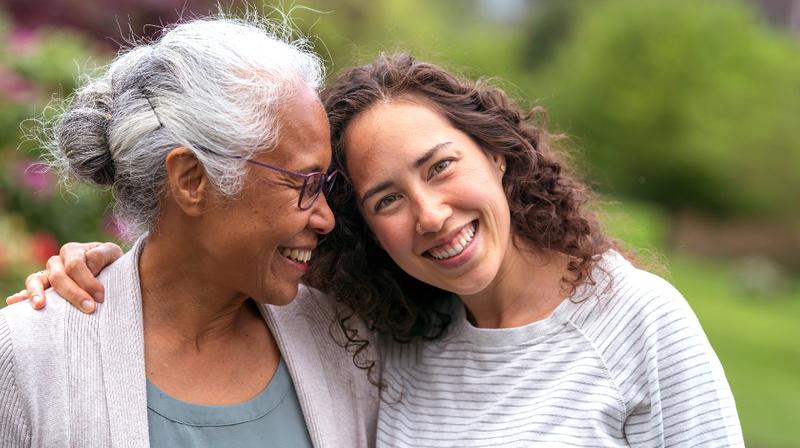 An older woman hugs her daughter.