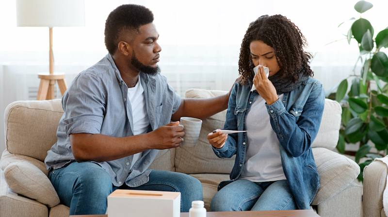 A young man tends to his sick partner at home.