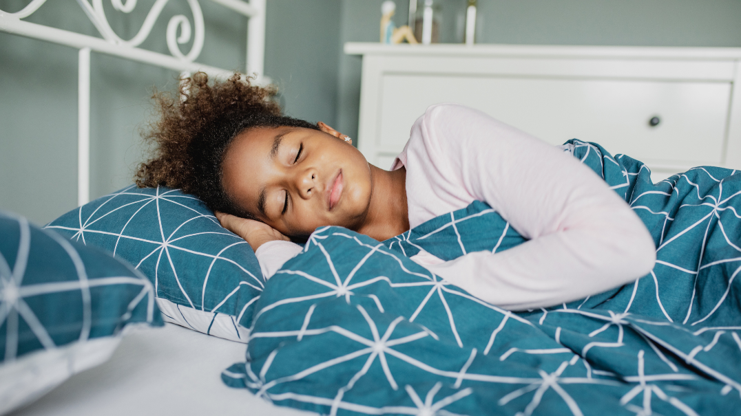 A young girl lays in her bed and sleeps.