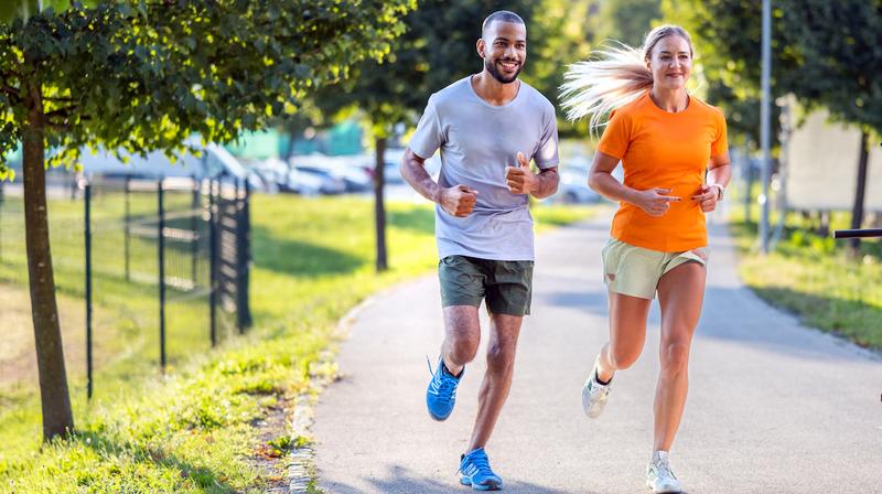 A man and a woman jog together in a park.