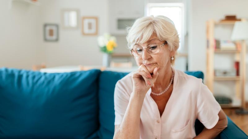 A woman sits on her livingroom sofa and ponders.