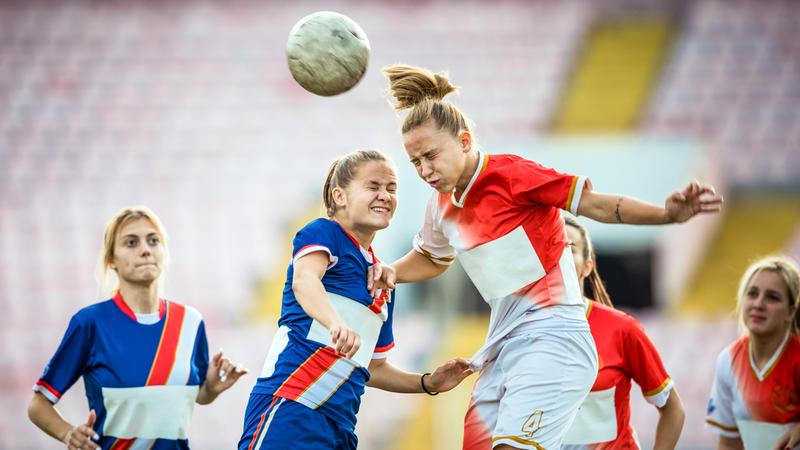 Two young soccer players head the ball during a soccer game.