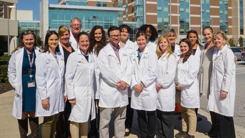 The faculty of the Family Medicine Residency program poses for a photo outside with MedStar Franklin Square hospital in the background