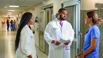 Two cardiovascular disease fellows consult with a nurse in a hospital setting.
