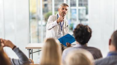 Male doctor teaching a seminar to students in a board room