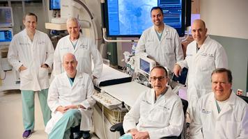 A team of MedStar cardiology doctors stand in a cardiac catheterization lab surrounded by modern technologic equipment.