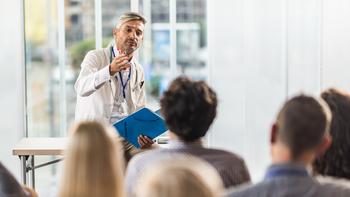 Male doctor teaching a seminar to students in a board room