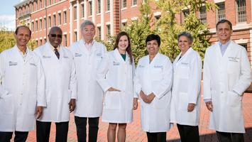 A group of physicians from the Neonatal Perinatal Medicine Fellowship Program at MedStar Georgetown University Hospital pose for a photo outdoors. All of the people are wearing masks.