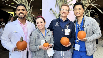 Graduates from the Pulmonary Critical Care Medicine Fellowship stand outside to pose for a photo at a fall festival.