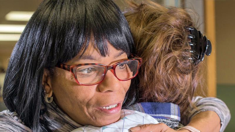 A woman provides a hug of support to a person going through substance abuse treatment.