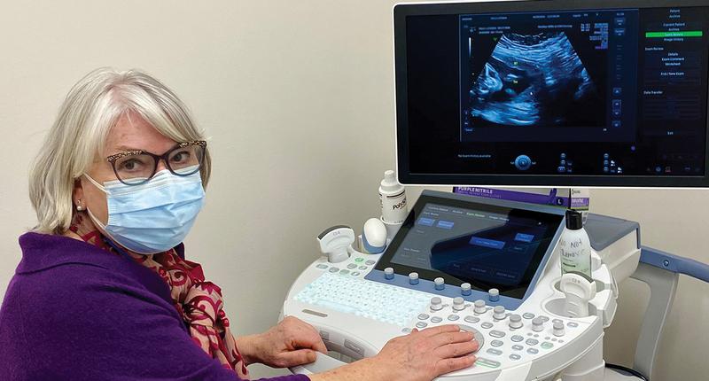 Dr Melissa Fries poses for a photo in front of an ultrasound machine.