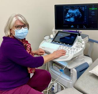 Dr Melissa Fries poses for a photo in front of an ultrasound machine.