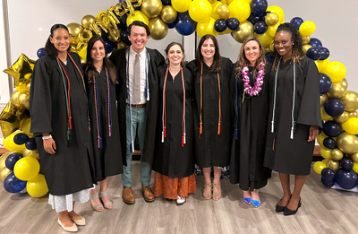 MedStar Health's Family Medicine Residency - Baltimore class of 2023 - wearing caps and gowns and standing in front of a balloon arch.