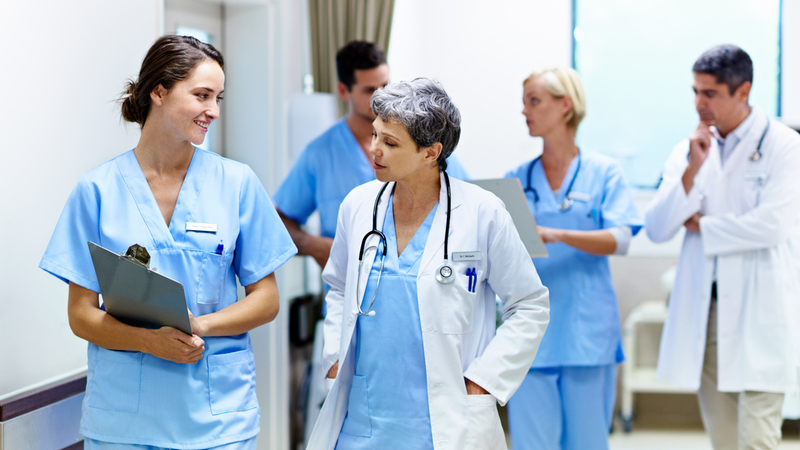 Doctors and medical students talk while walking in a hospital hallway.