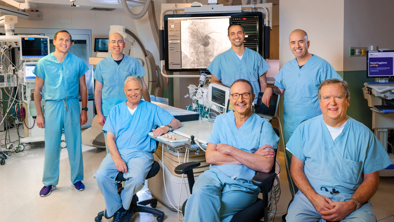 A team of MedStar cardiology doctors stand in a cardiac catheterization lab surrounded by modern technologic equipment.