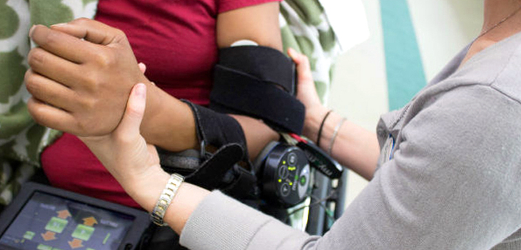 Close up photo of a rehabilitation specialist working with a patient who is wearing a hinged elbow brace.