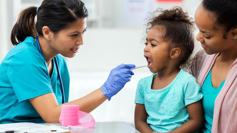 A healthcare provider treats a young patient in an urgent care setting.