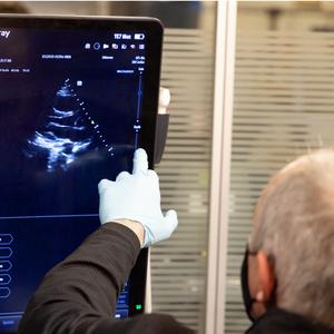 An ultrasound technician touches a computer screen during a scan.