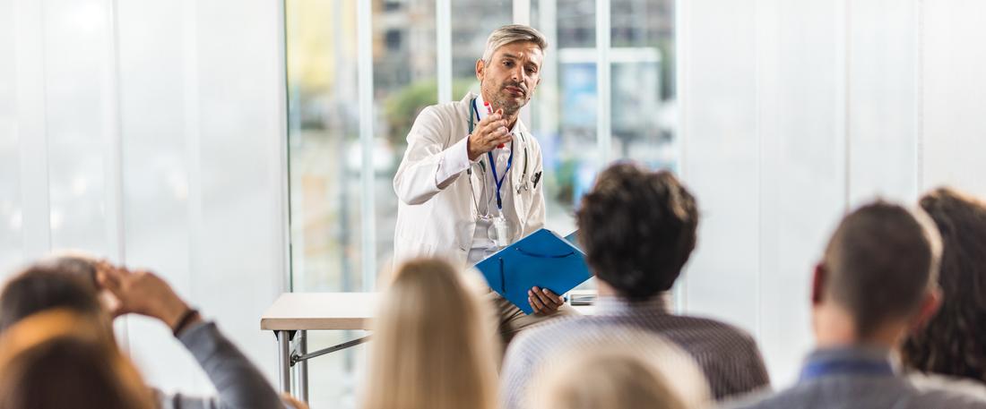 Male doctor teaching a seminar to students in a board room