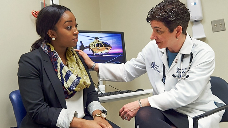 Dr Claudine Isaacs rests her hand on the shoulder of her patient while talking to her.