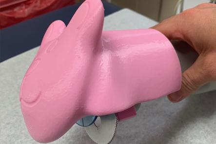 一个近距离照片的石膏锯盖在一个粉红色的兔子，用来切断石膏从儿科骨科病人。